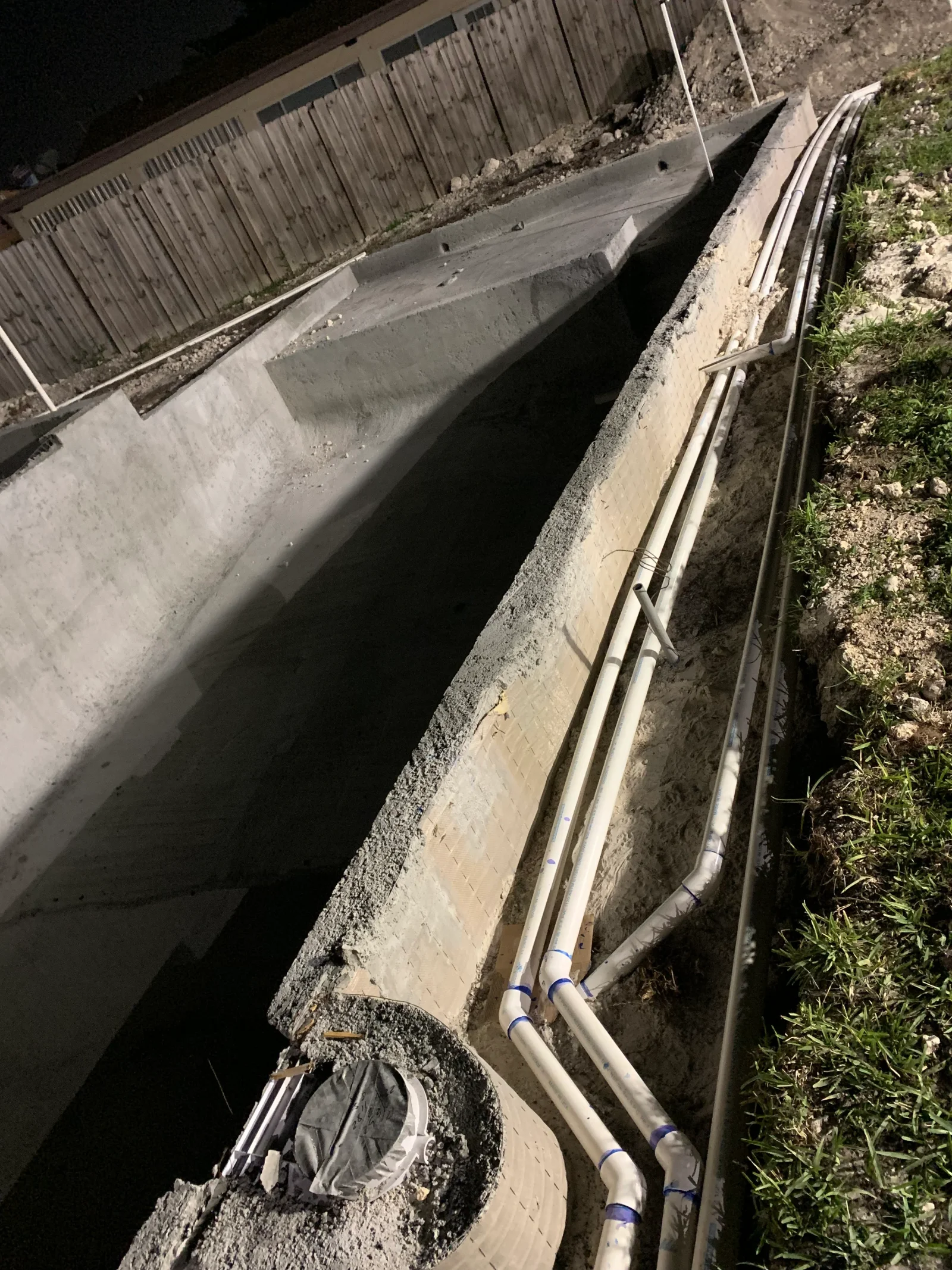 Concrete foundation walls with PVC conduit and utility lines installed in trench