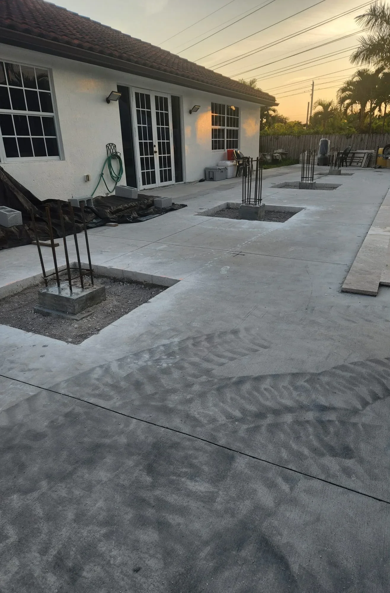 Concrete patio with control joints, rebar footings, and finished gray concrete surfaces during installation