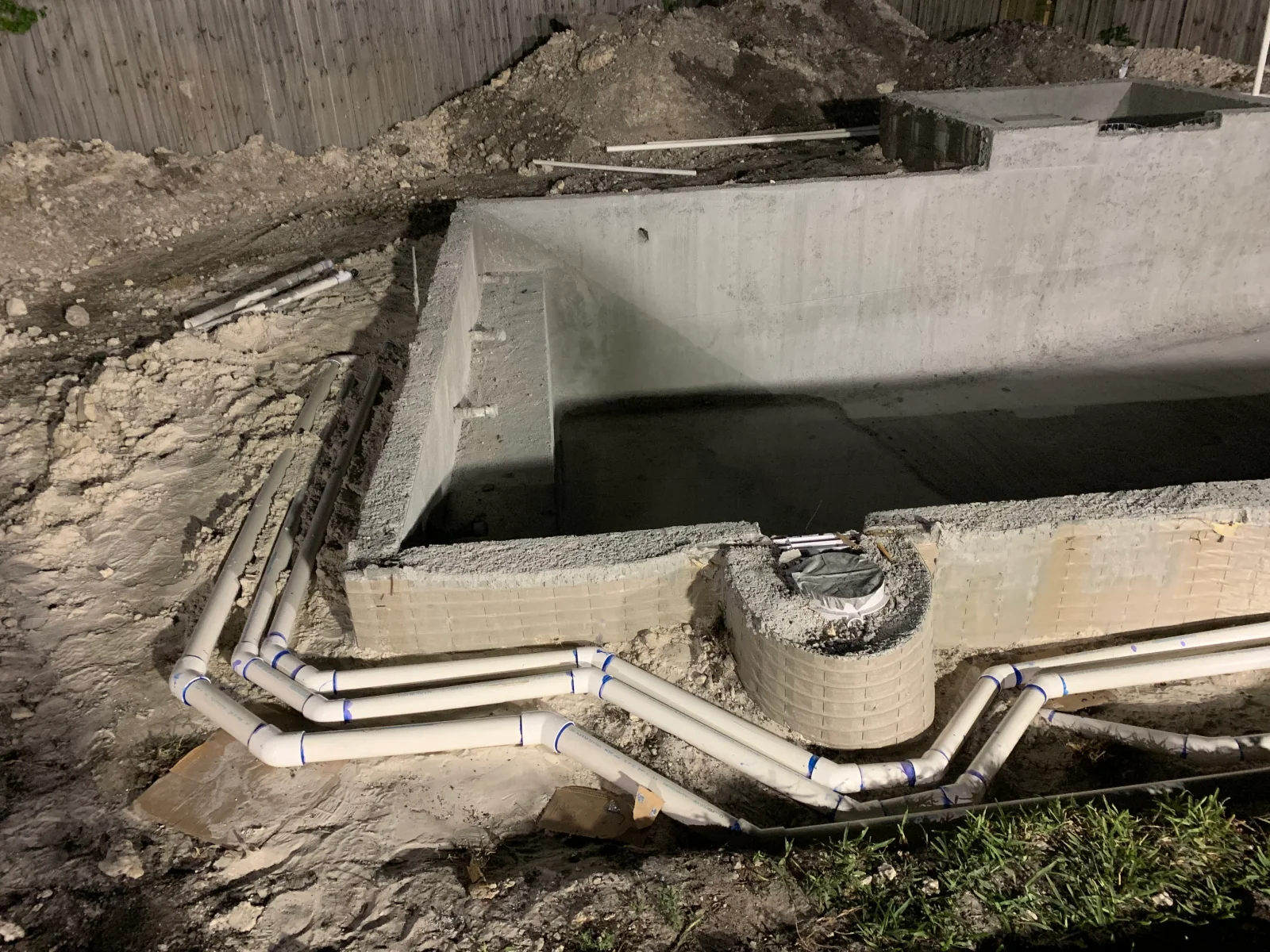 PVC pipes with blue couplings installed through concrete foundation structure during underground utility work