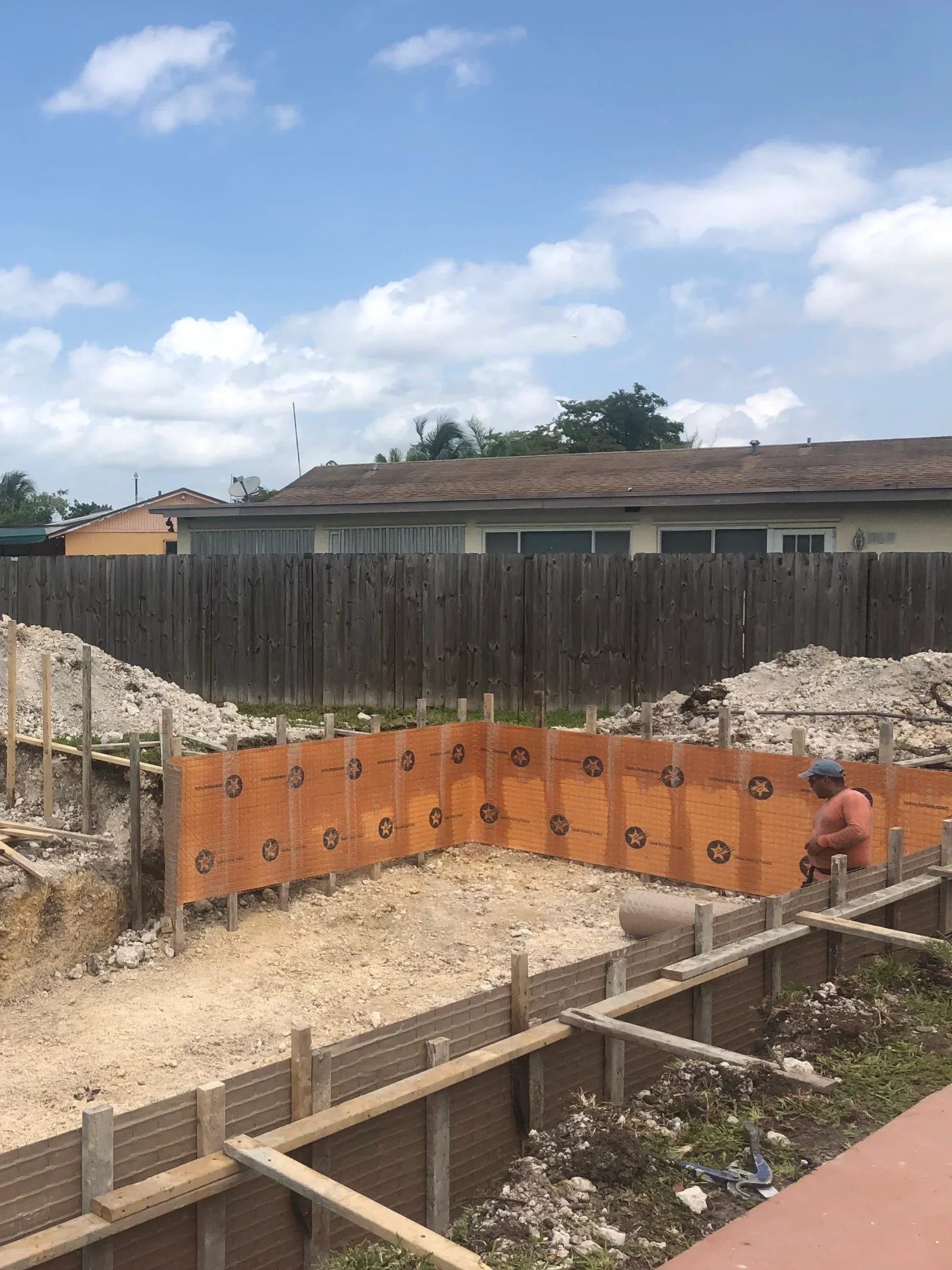 Wooden retaining walls with star patterns, concrete footers, and graded soil foundation work